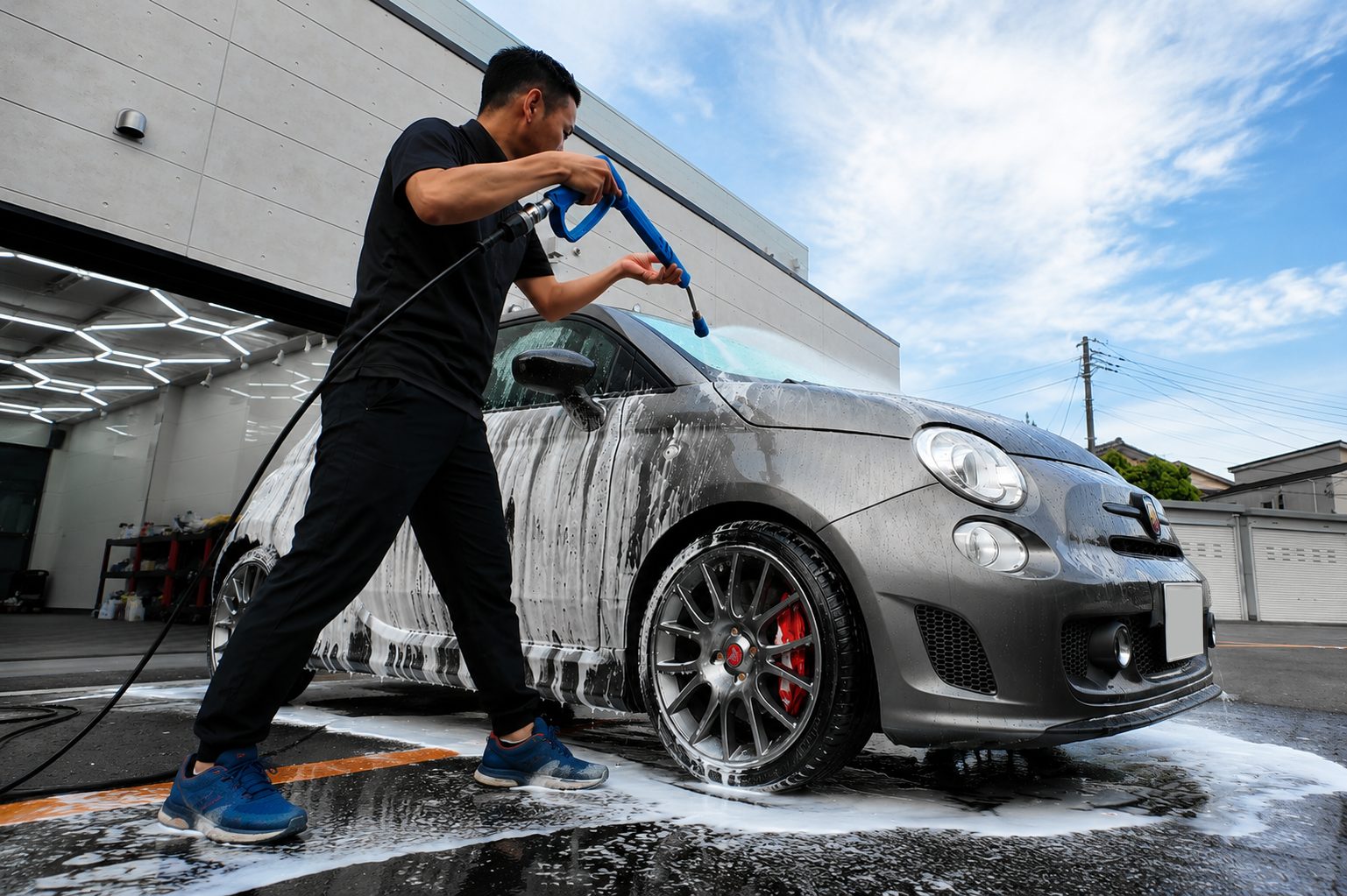 3pH洗車でボディの泡を洗い流すスタッフ