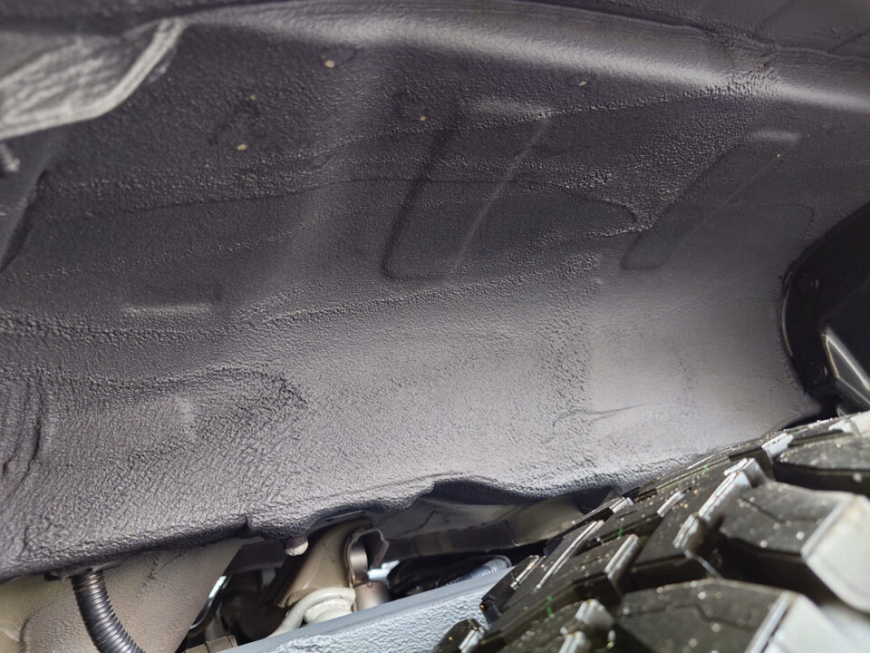 Under-dash view showing black textured insulation panel inside a car cabin.