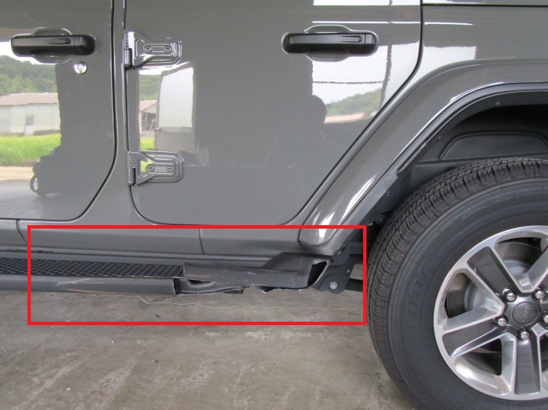 Gray SUV side view showing a crushed rocker panel and a detached running board under the doors near the rear wheel area.
