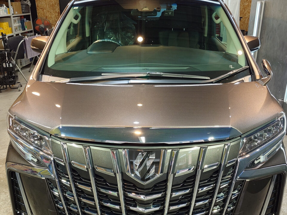Front view of a metallic brown SUV in a garage, showcasing a large chrome grille and headlights.