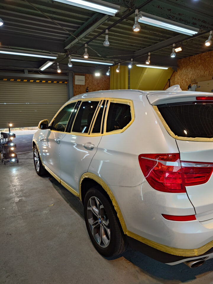 ディテーリングブース内でマスキングを行い研磨準備を進めるBMW X3